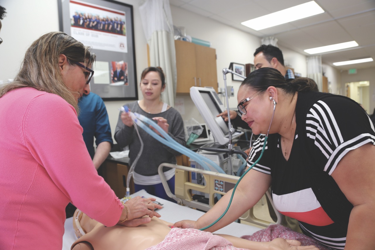 students in a classroom performing CPR to a model inside a lab