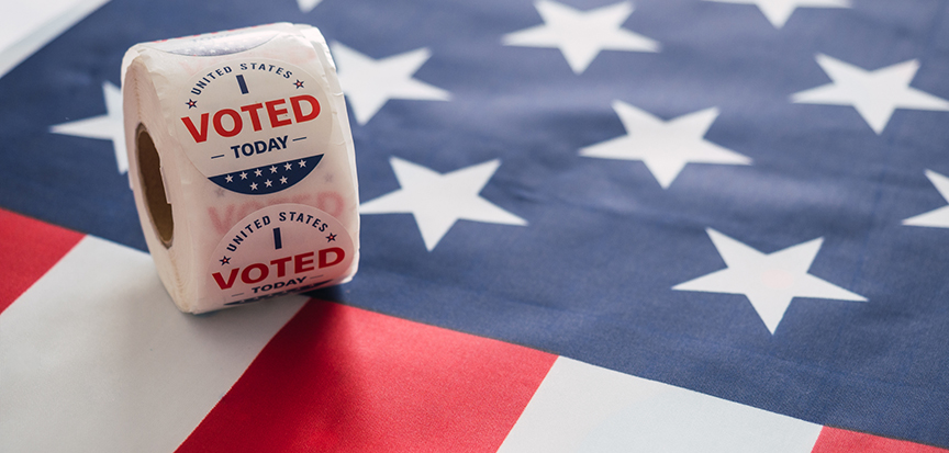 Roll of voting booth participation stickers on top of an American flag