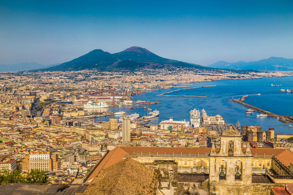 Italian coastal city with view of Mount Etna in background