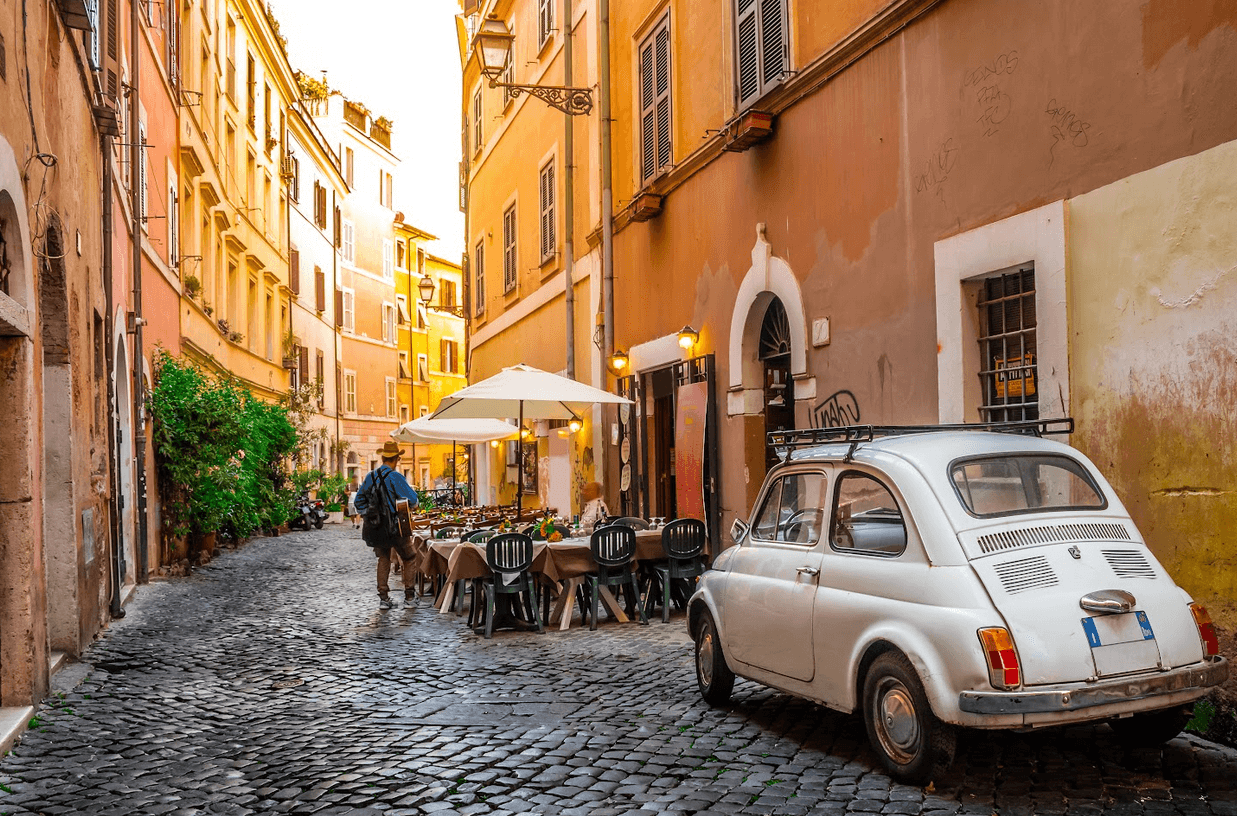 man walking away from a vintage European car parked in a side street in Rome